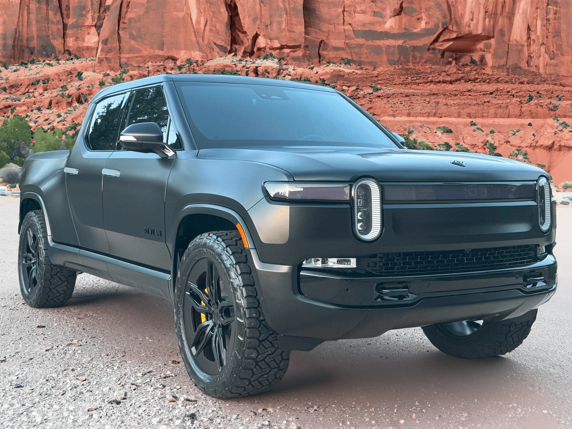 Rivian R1T R1S Project Midnight R1T front passenger grey dirt road moab cliffs in background small
