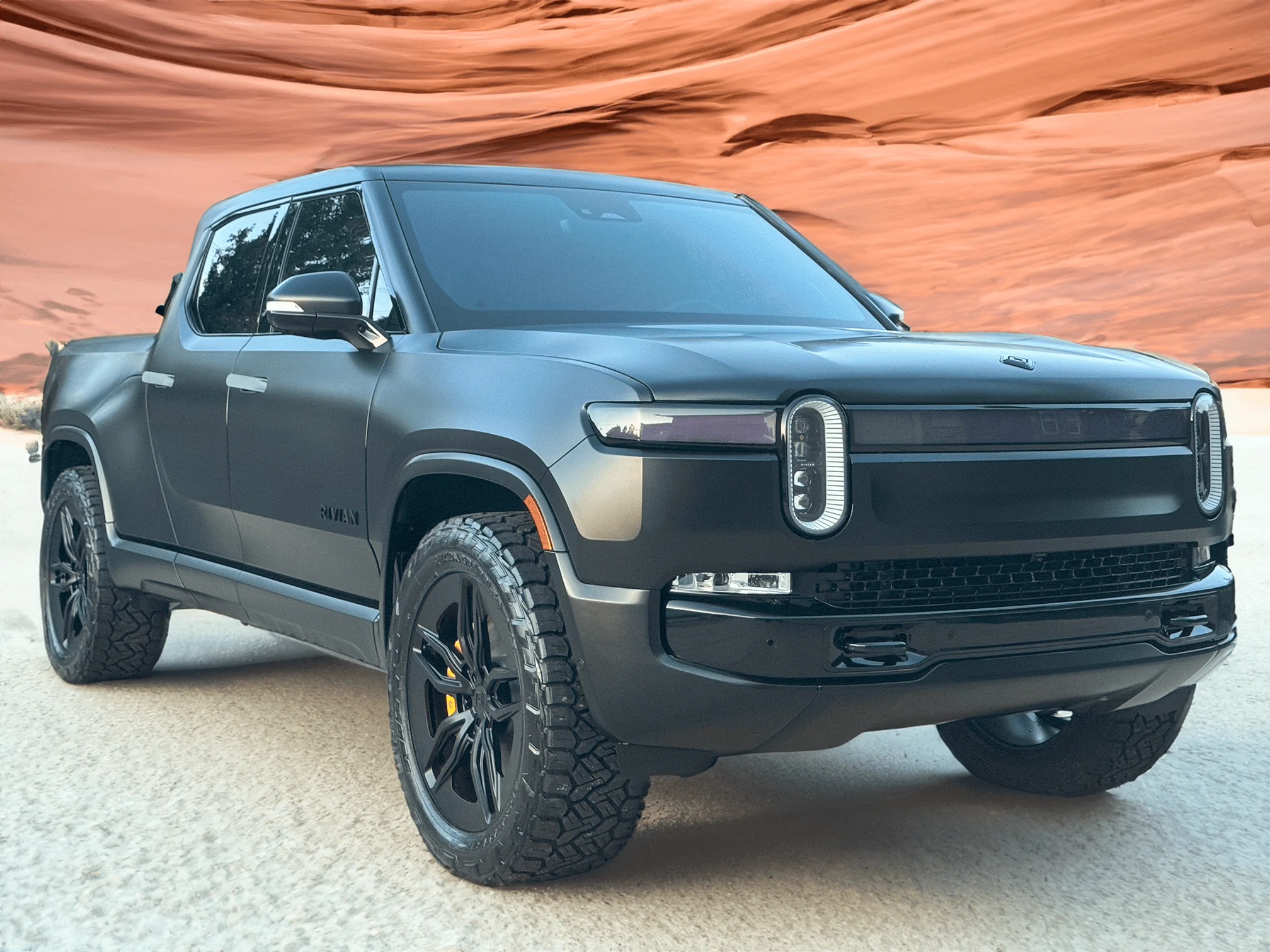 Rivian R1T R1S Project Midnight R1T er-in-sand-with-the-wave-red-rock-behind-small-png