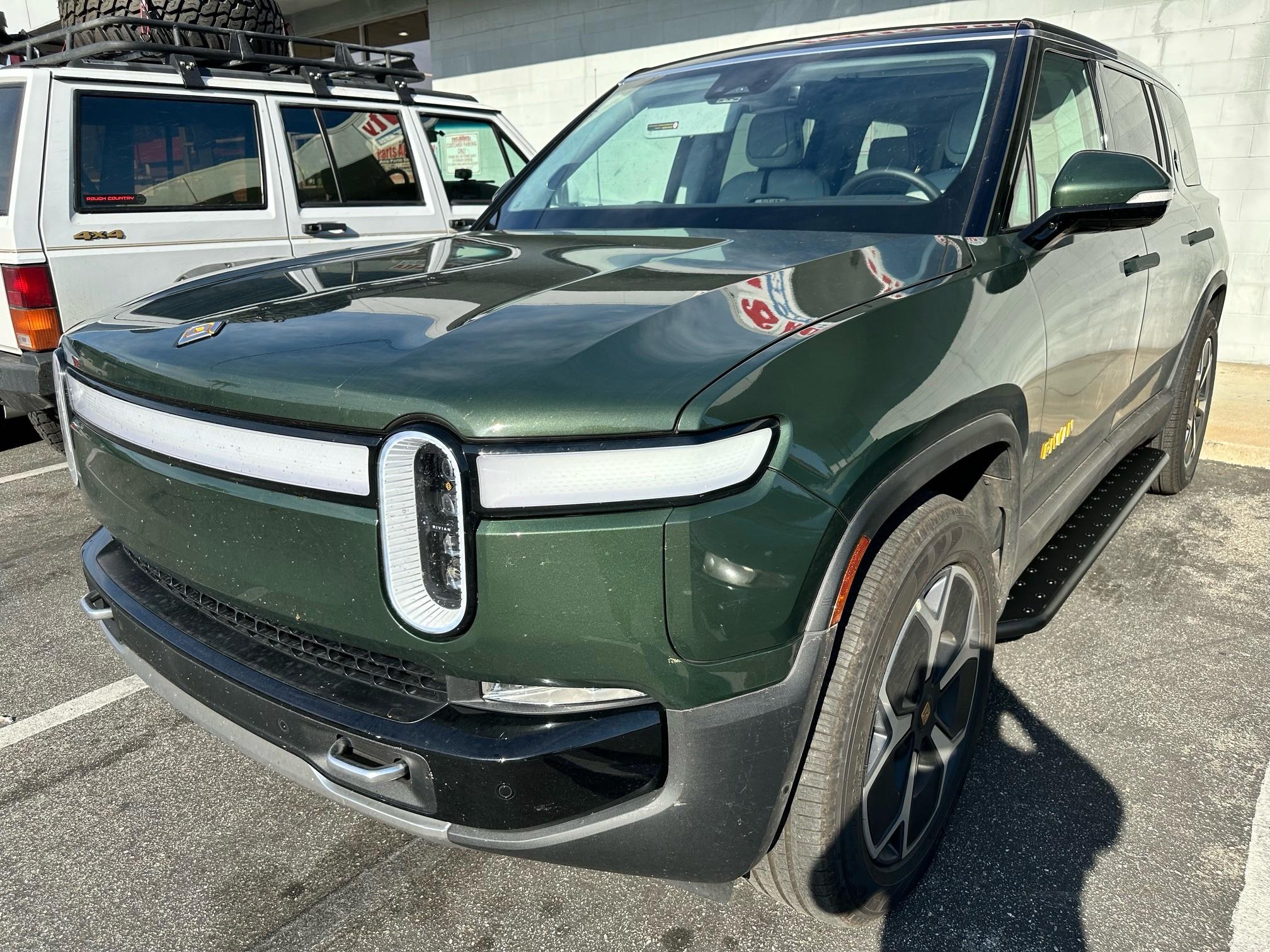 Rivian R1T R1S RealWheels EV Stainless Steel Running Boards Black Running Boards on Green R1S