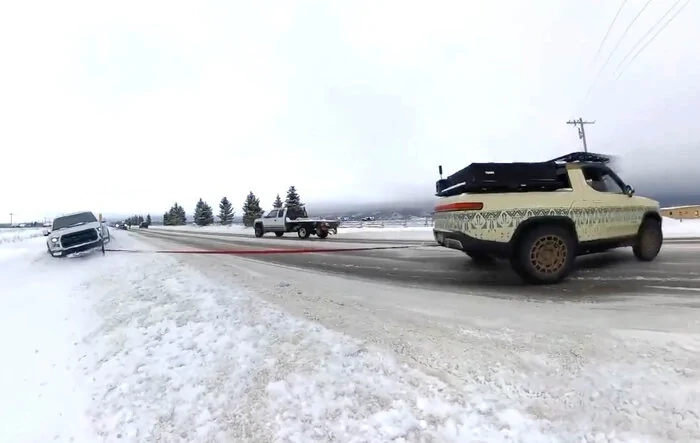 Rivian R1T pulls a stuck F-150 Raptor out of the snow [video]